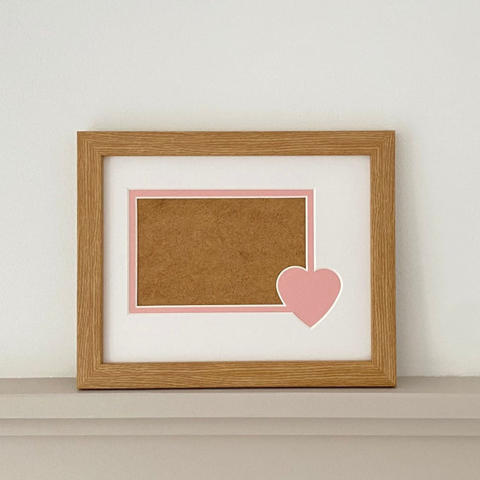 Pink heart mount and light brown frame on grey shelf